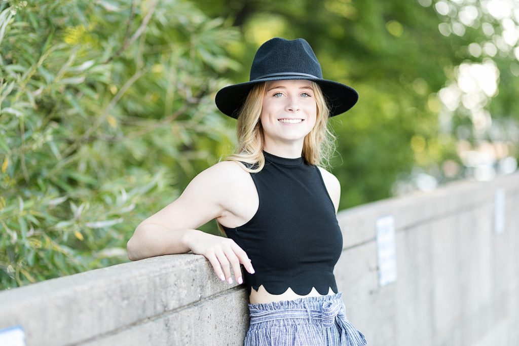 girl with a black hat on leaning against a concrete wall in Eau Claire for Boho Senior Photos