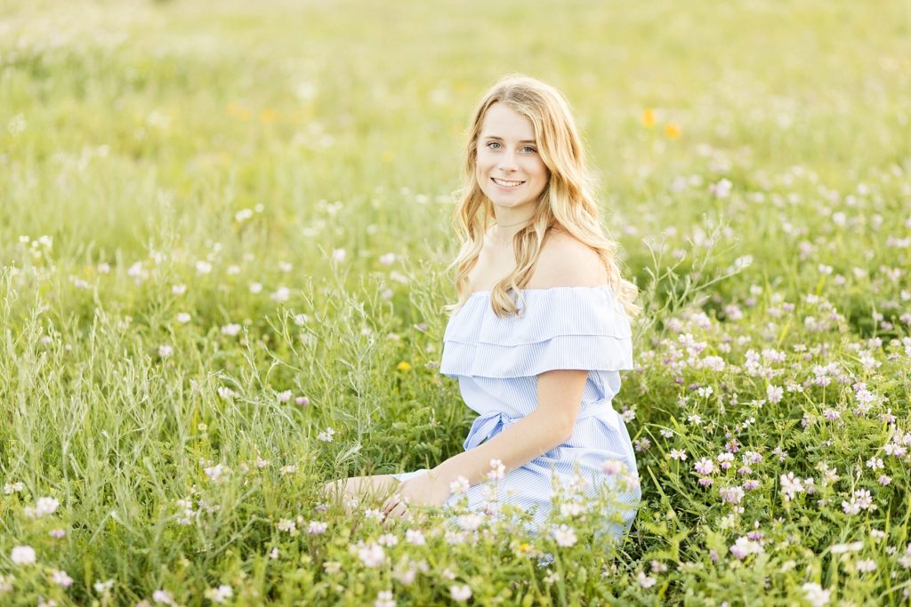 girl sitting in a field of flowers for boho style senior photos