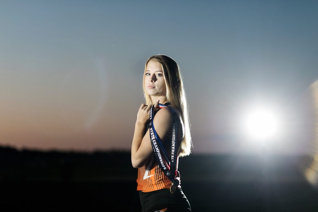 girl holding state champion medals for relay in track
