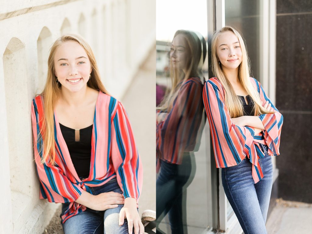 girl in a brightly colored striped top on a bridge and leaning against glass for her Eau Claire boho senior photos