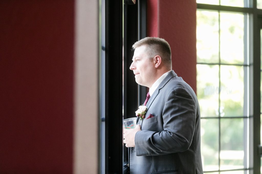 groom looking out the windows at the ceremony location at the Glacier Canyon Conference Center for a wedding at the Wilderness Resort in Wisconsin Dells