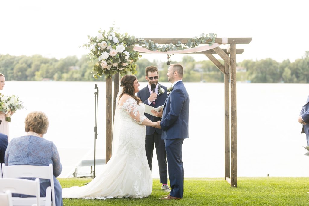 couple holding hands on the lawn at their wedding ceremony at Lake Wissota Golf & Events