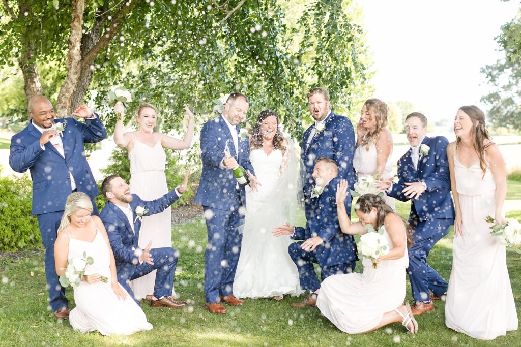 groom popping a champagne bottle and spraying it with the bridal party at Lake Wissota Golf & Events