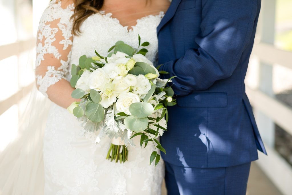 bride and groom holding a white and green wedding bouquet by Brent Douglas Flowers at Lake Wissota Golf & Events