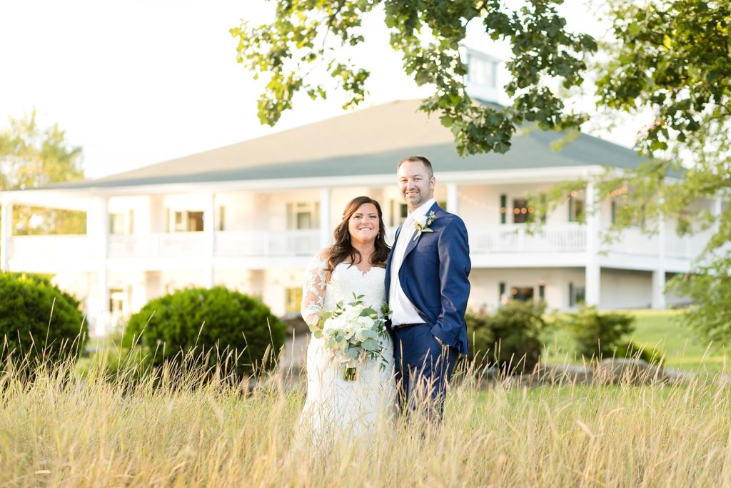 couple standing in tall grass infront of the building at Lake Wissota Golf & Events