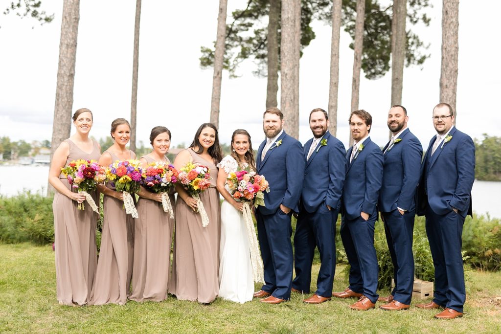 bride and groom with wedding party infront of the lake smiling at The Beacons of Minocqua on their wedding day