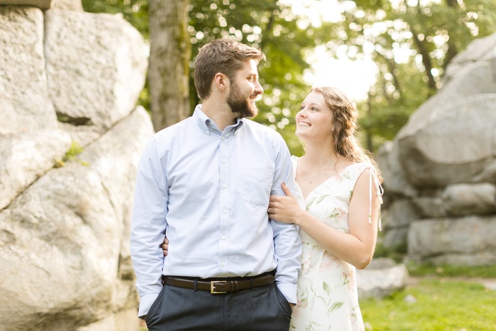 couple near rock formations smiling at each other near the spot where he proposed at Rib Mountain State Park in Wausau for their engagement pictures