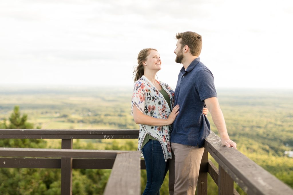 couple on top of the tower at Rib Mountain State Park in Wausau for their engagement pictures where he proposed