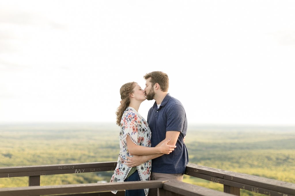 couple kissing on top of the tower Rib Mountain State Park in Wausau for their engagement pictures