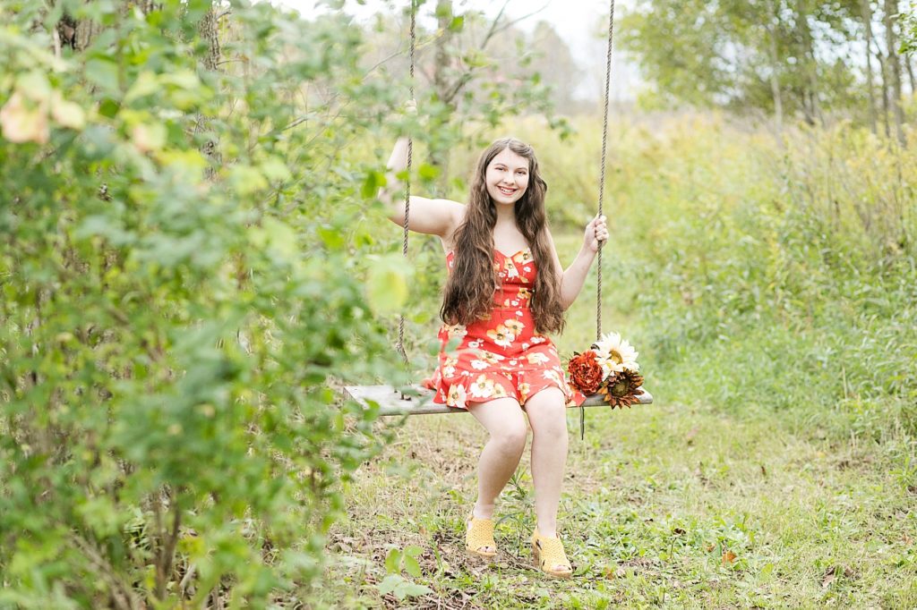 girl on a wood and rope swing in a field for her Cadott High School senior photos