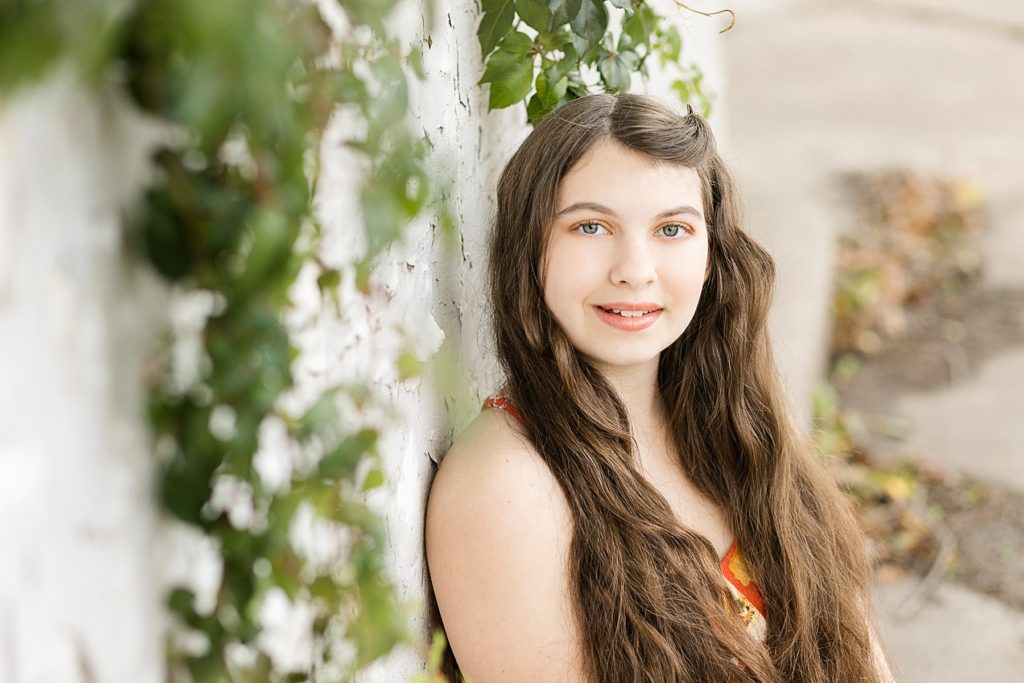girl leaning on a vine covered wall for her Cadott High School senior photos