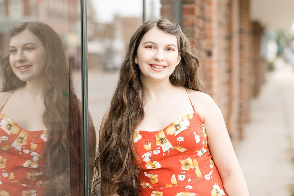 girl in downtown Bloomer leaning on a brick wall for her Cadott High School senior photos