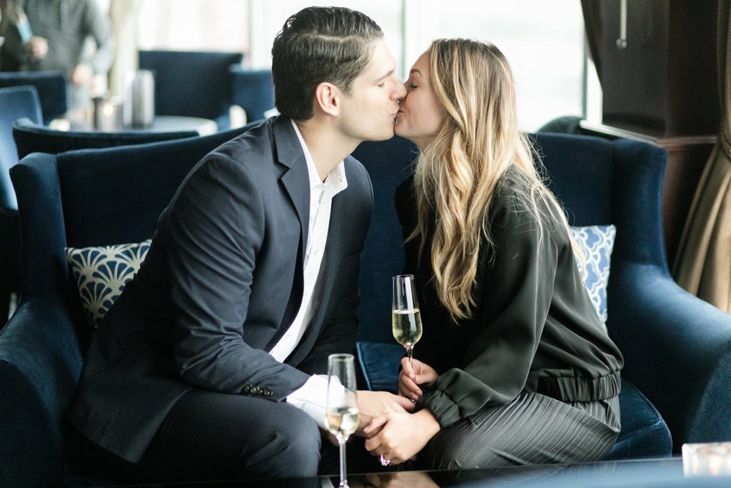 couple kiss with glasses of champagne in Blu at the top of the Pfister Hotel in Milwaukee