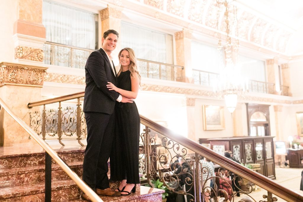 couple on the stairs above the lobby in the Pfister Hotel after he proposes at the Milwaukee Art Museum