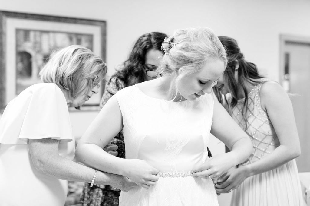 bride with her mom and bridesmaid getting dressed in Chippewa Falls