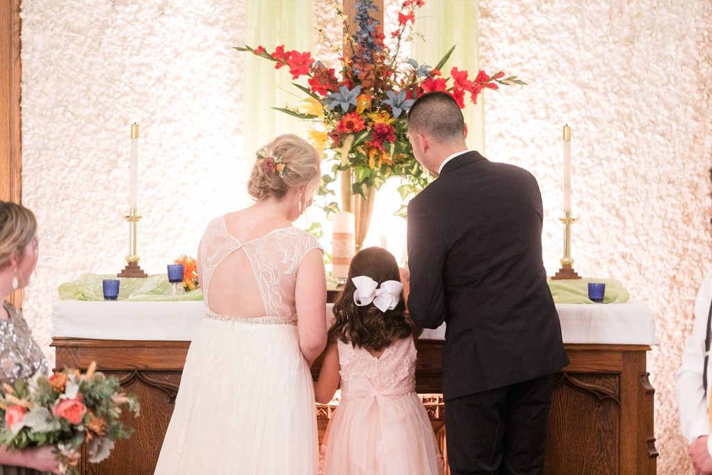 bride, groom and daughter lighting the unity candle at wedding at Zion United Methodist Church in Chippewa Falls