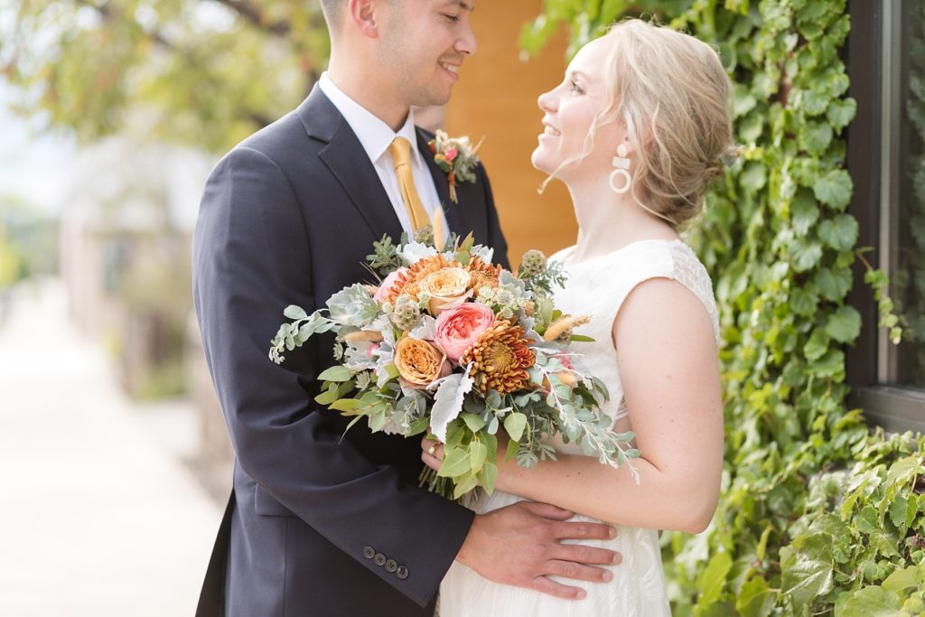 couple near vines outside at their wedding at the Oxbow Hotel in Eau Claire