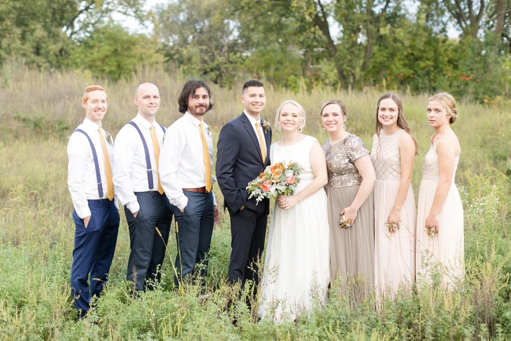 bridal party in a field at their wedding at the Oxbow Hotel in Eau Claire