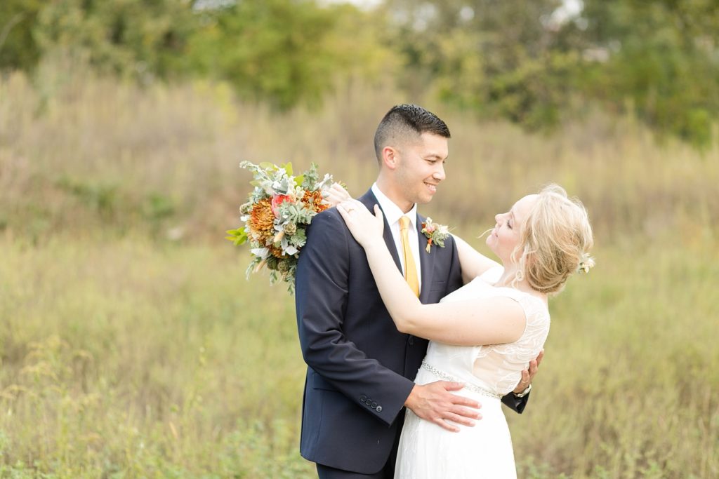 couple in a field on their wedding day at their wedding at the Oxbow Hotel in Eau Claire