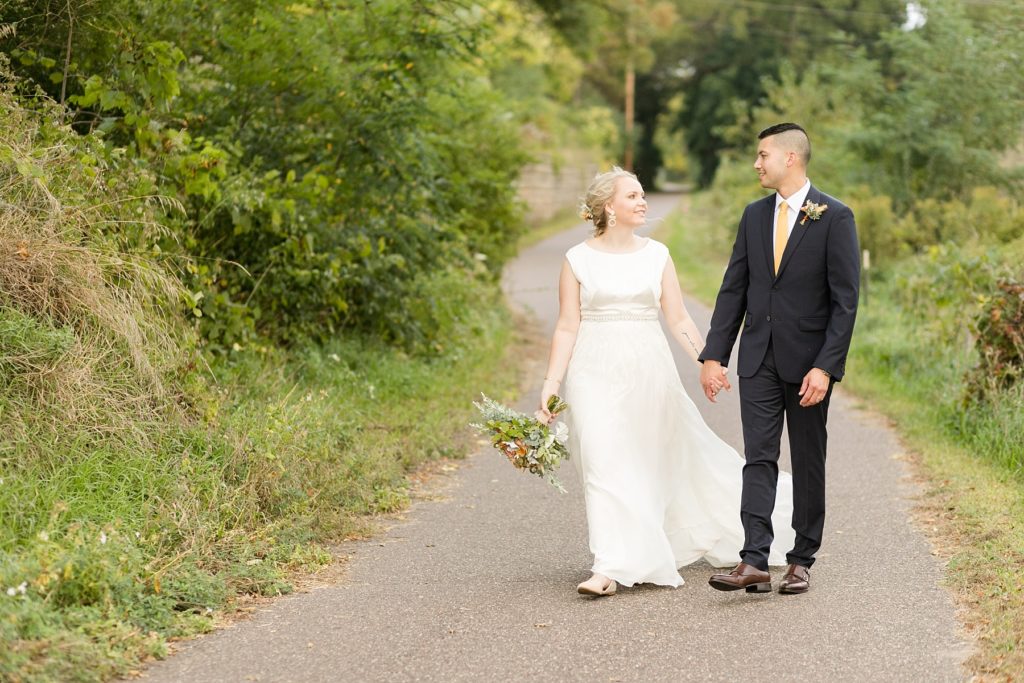 couple smiling at each other on the bike path at their wedding at the Oxbow Hotel in Eau Claire