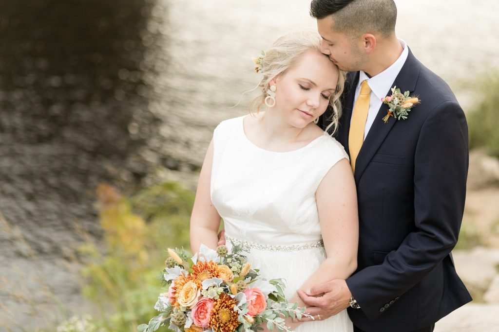 couple in a tender moment near the river at their wedding at the Oxbow Hotel in Eau Claire