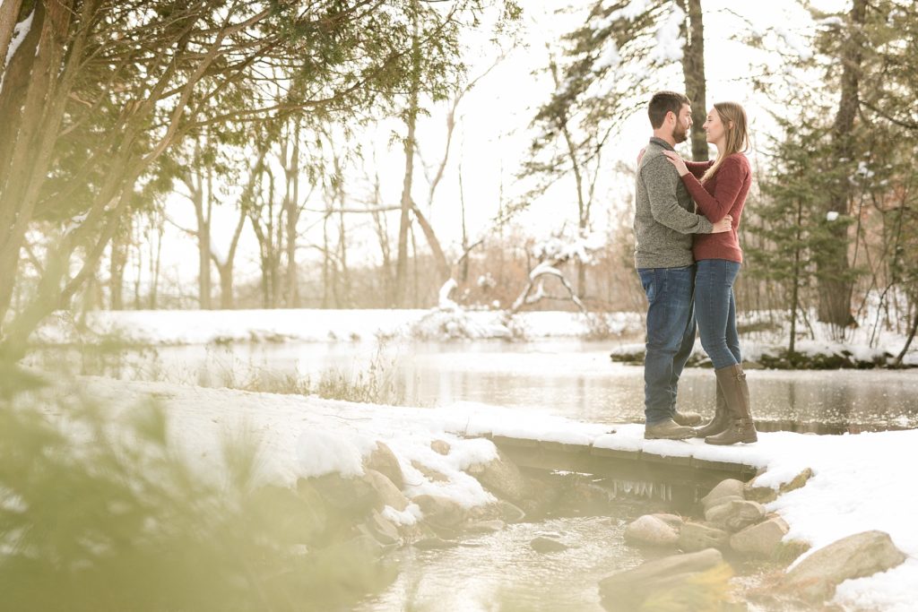 couple on a small bridge in Eau Claire for their engagement session in the winter