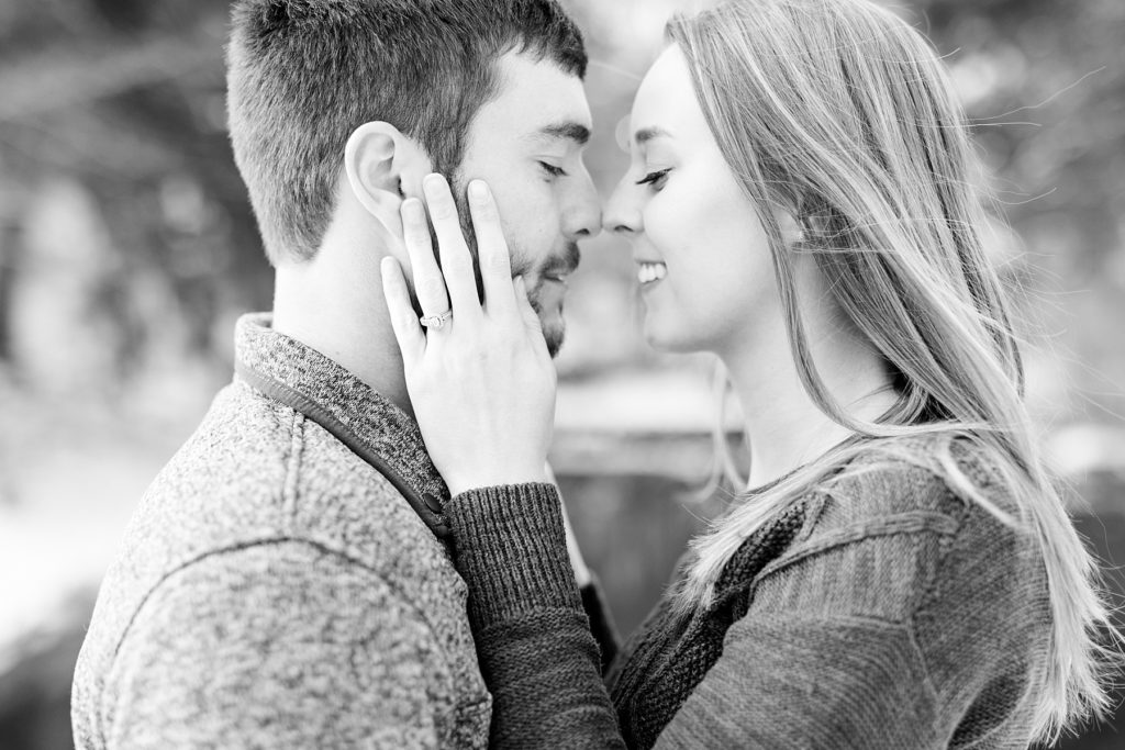 couple in a black and white photo nose to nose outside for their winter engagement photos in the snow