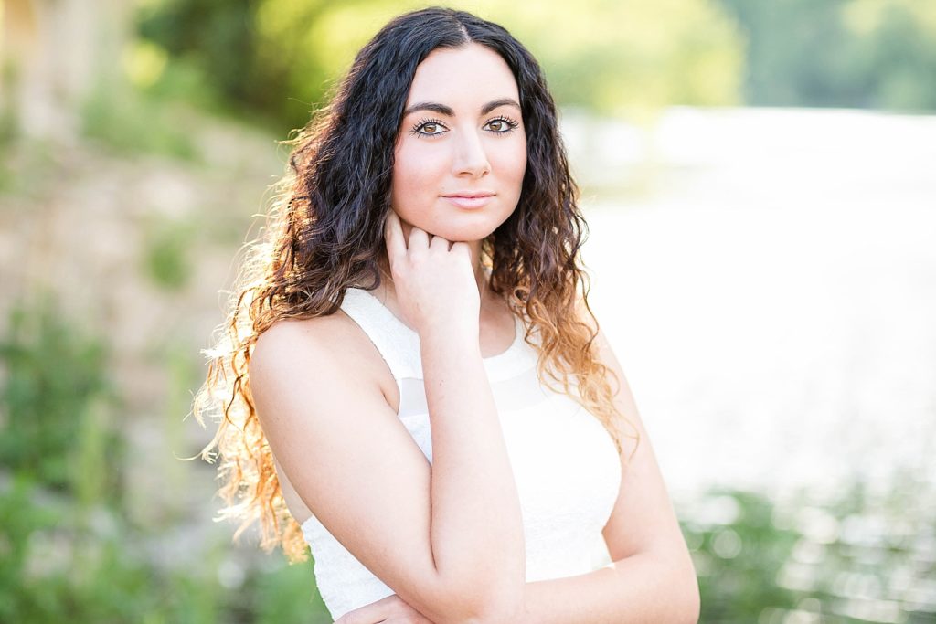 girl looking at camera in white dress with glowing light for her Eau Claire senior photos
