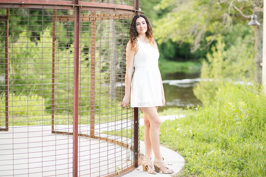 girl in a white dress leaning on a corn crib for her Eau Claire senior photos