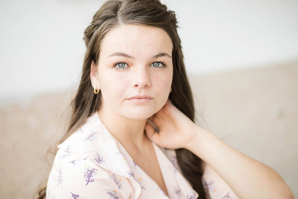 girl sitting with a floral top on looking at the camera for her boho senior session in Eau Claire, WI