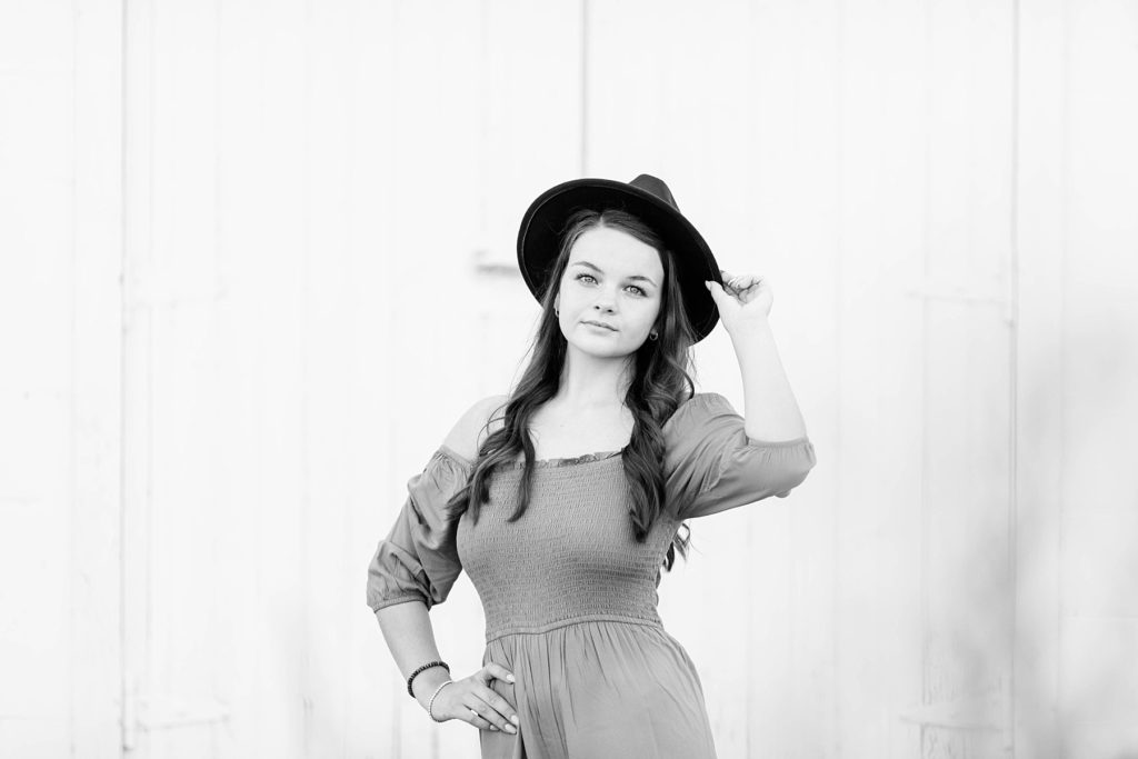 girl in a black and white photo holding onto a black hat for her boho senior session in Eau Claire, WI