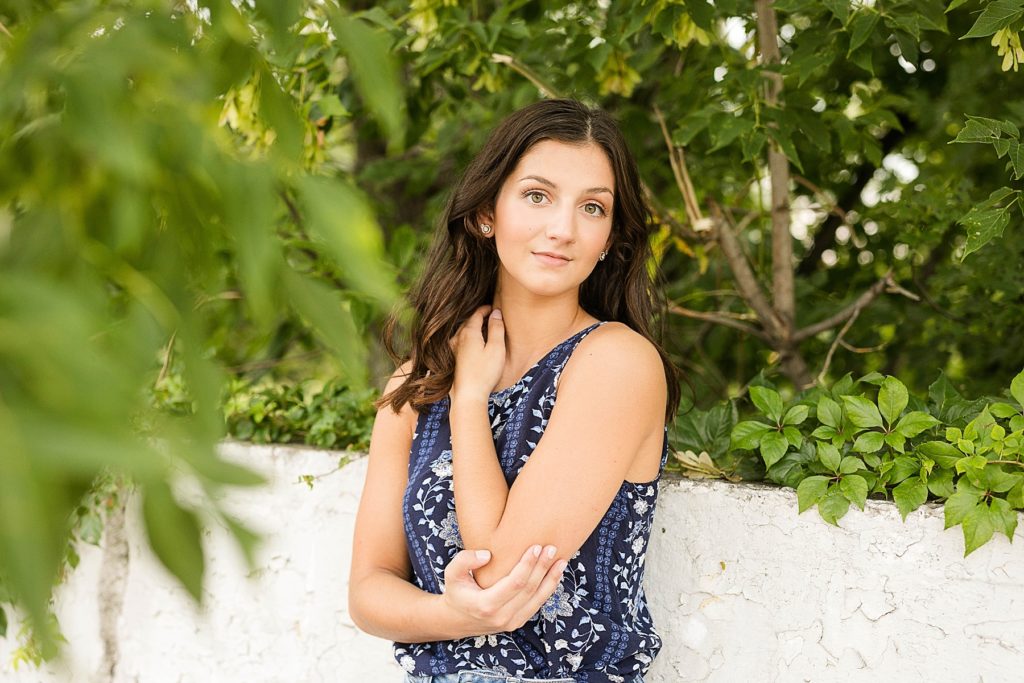 girl smiling at the camera through a tree and vines with a blue tank top on