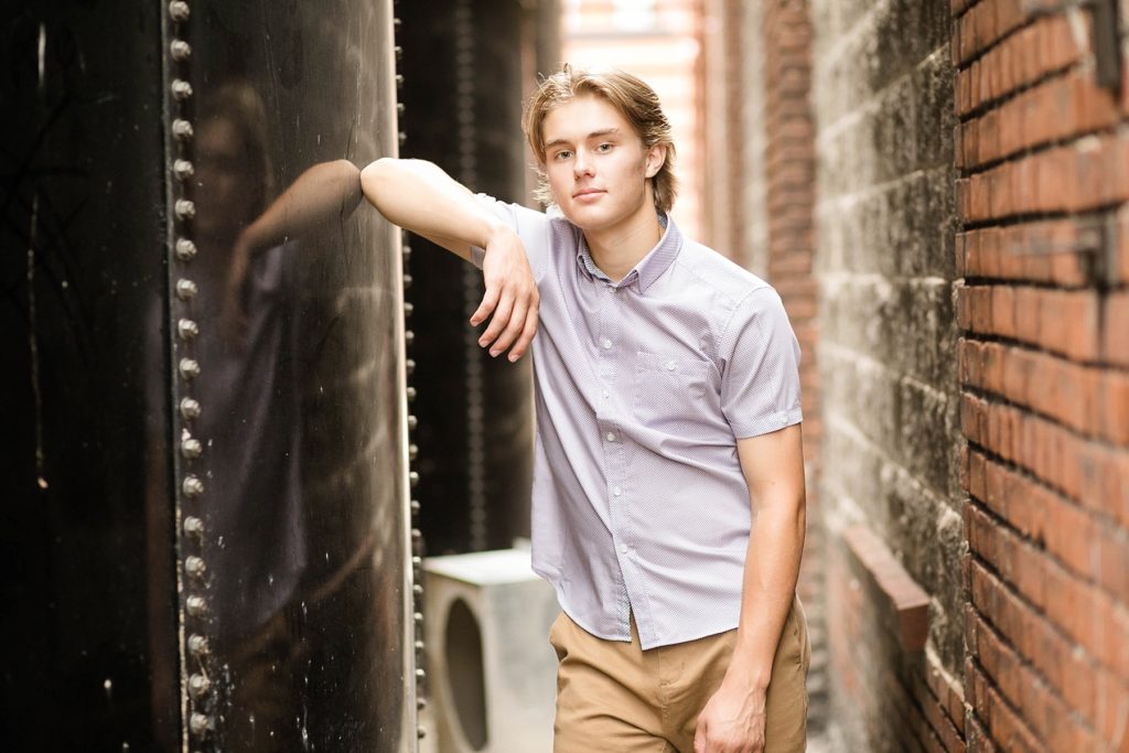 boy leaning on a black silo at Banbury Place in Eau Claire for his senior pictures