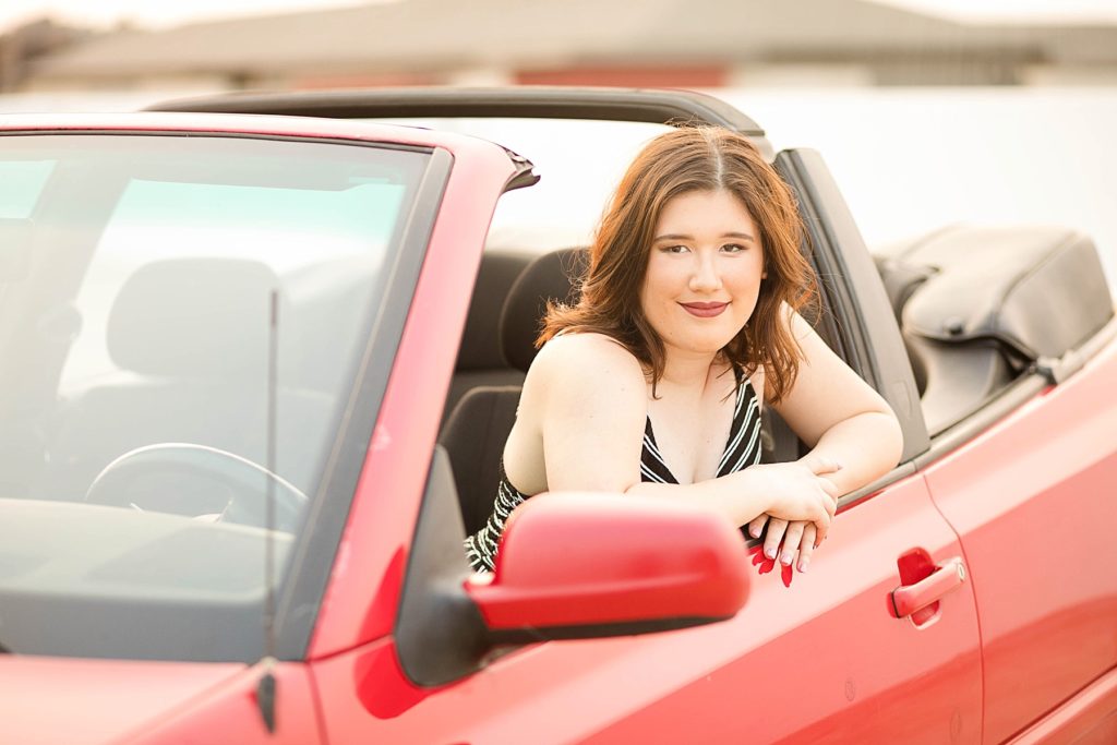girl leaning out of her red VW convertible in Eau Claire for her laid back senior photos