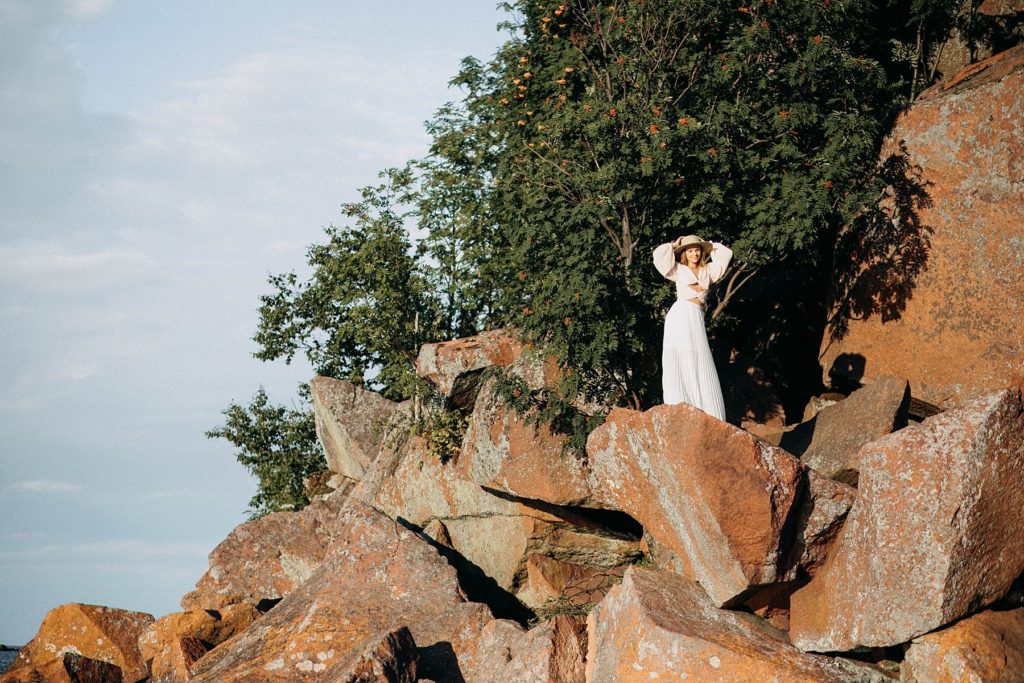 girl standing on rocks above Black Sand Beach in Silver Bay, MN for her senior photos