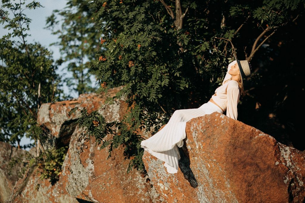 girl sits on rocks above Black Sand beach for her senior photos in Silver Bay, MN