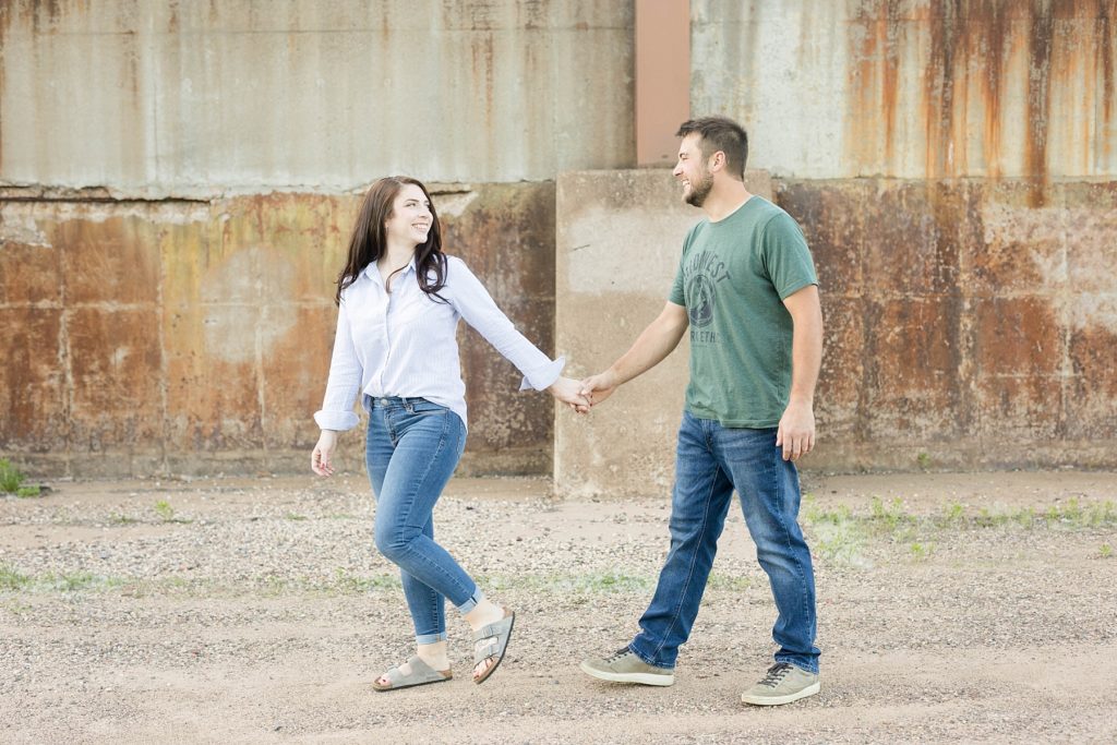 couple walking looking at each other in casual spring engagement photos in Eau Claire