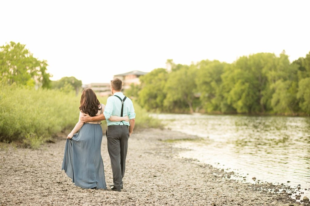 couple walking away on the river bank in Eau Claire for their summer engagement photos