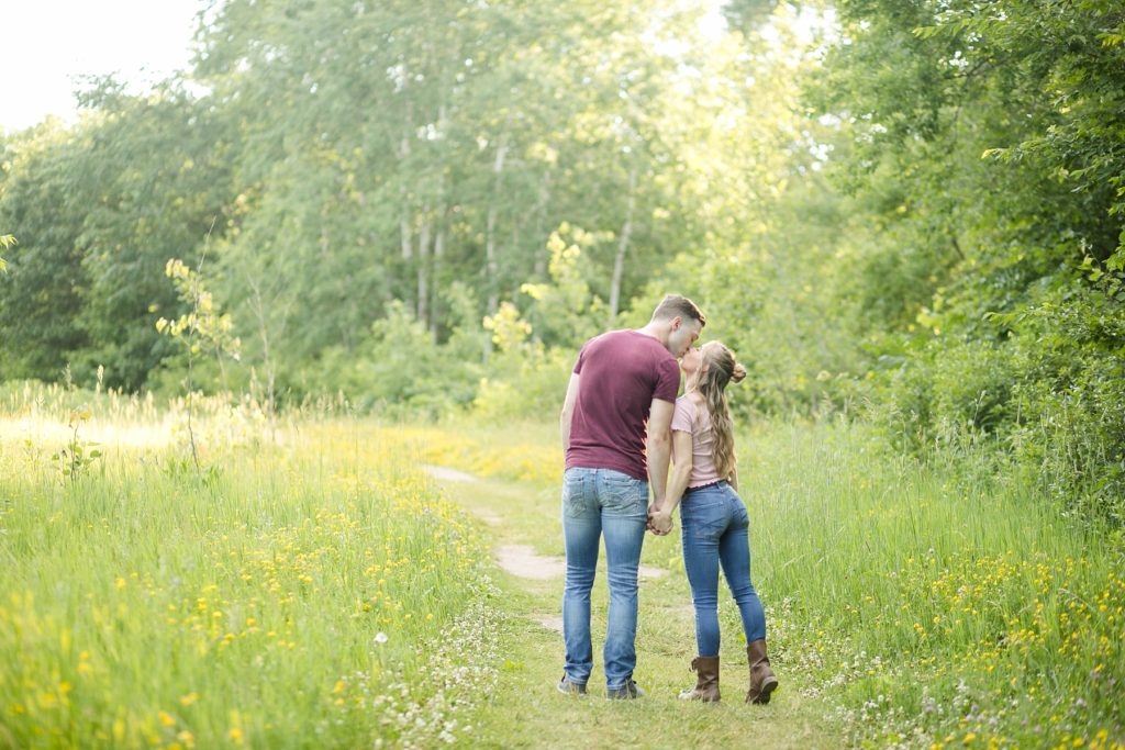 couple kissing on a trail in the summer at Willow River State Park in Hudson, WI for their engagement session