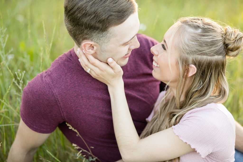 couple sitting in a field of flowers at Willow River State Park in Hudson, WI for their engagement session