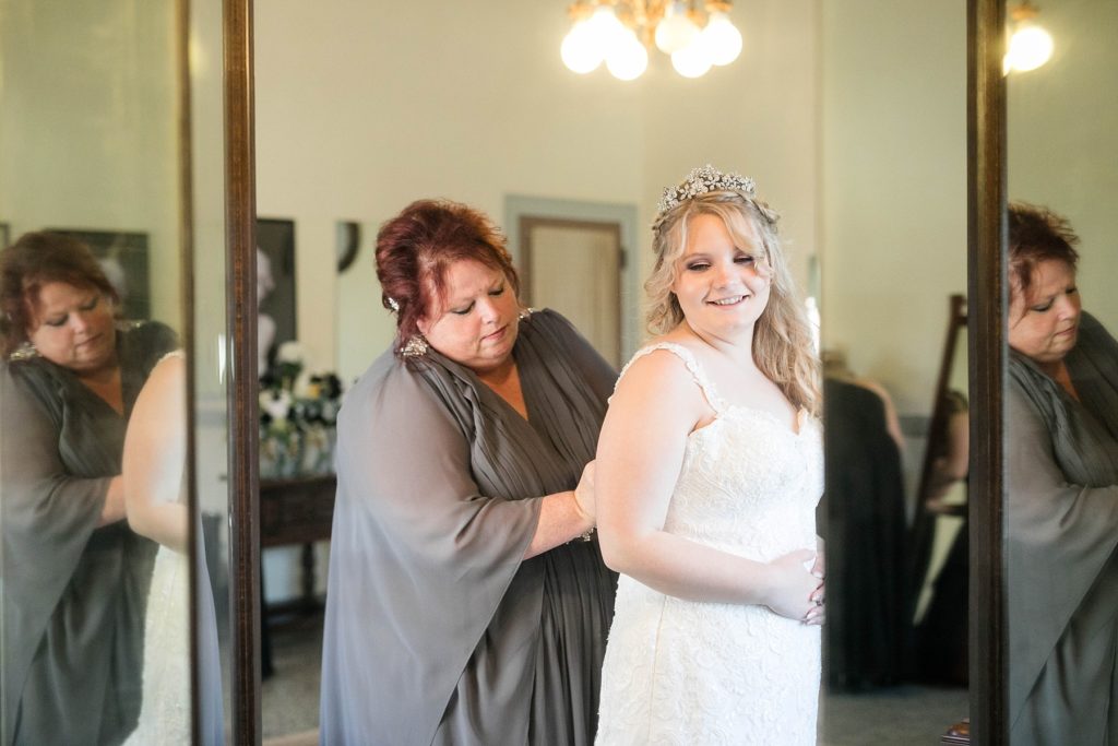 brides mom helping her into her gown  at Masonic Ballroom in Eau Claire