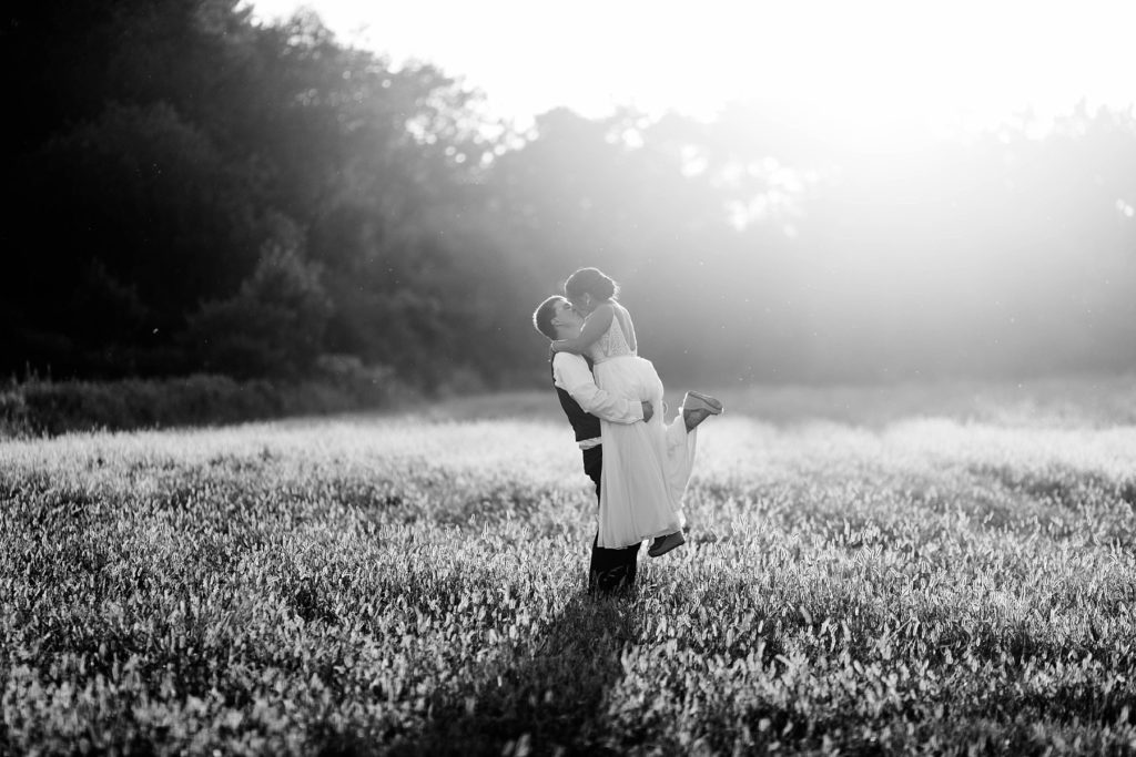 groom holding his bride in a field at Lilydale in Chippewa Falls