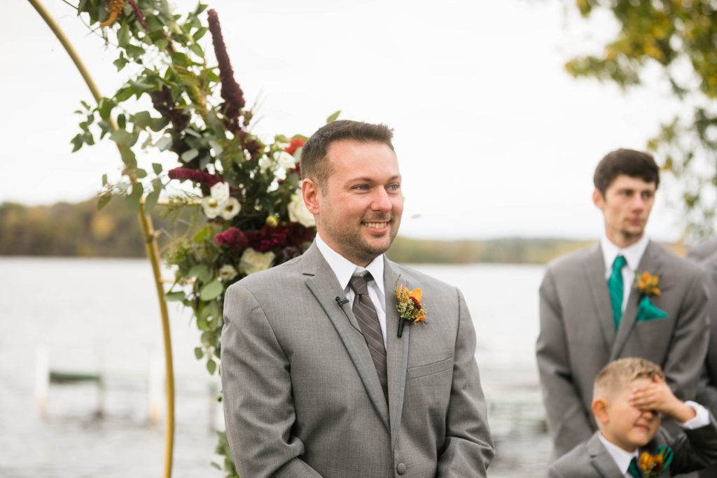 groom watching the bride walk down the aisle at a wedding at Lake Wissota Golf & Events