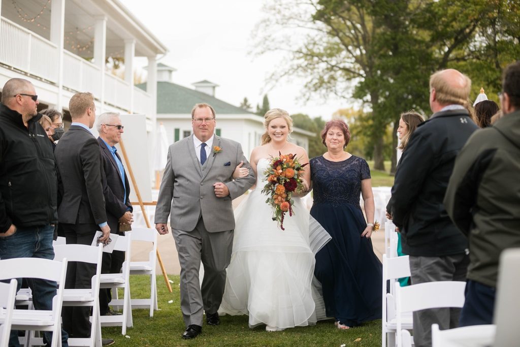 bride being walked down the aisle by her parents at a wedding at Lake Wissota Golf & Events