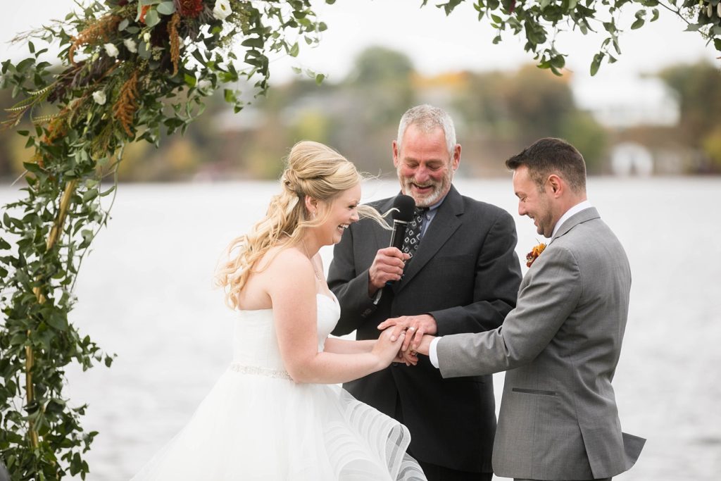 bride and groom exchange their rings on the lake shore at a wedding at Lake Wissota Golf & Events