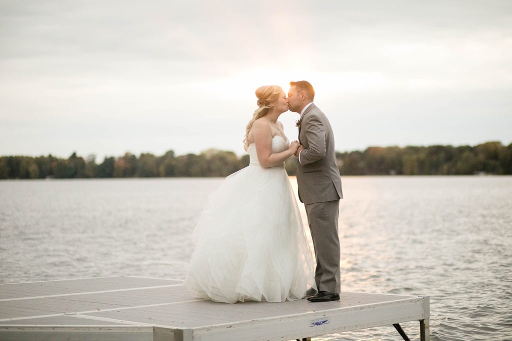 couple kissing on the dock at sunset at a wedding at Lake Wissota Golf & Events