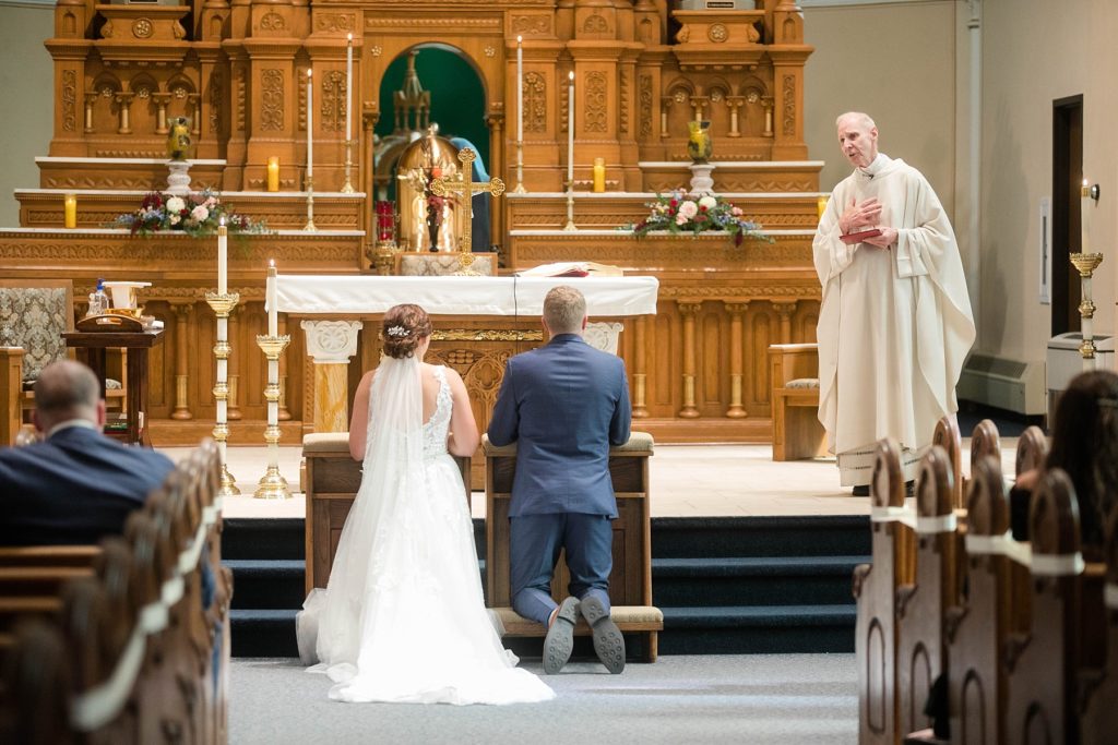 priest speaking to the couple at stunning wedding in Marathon, WI at St. Mary's Catholic Church