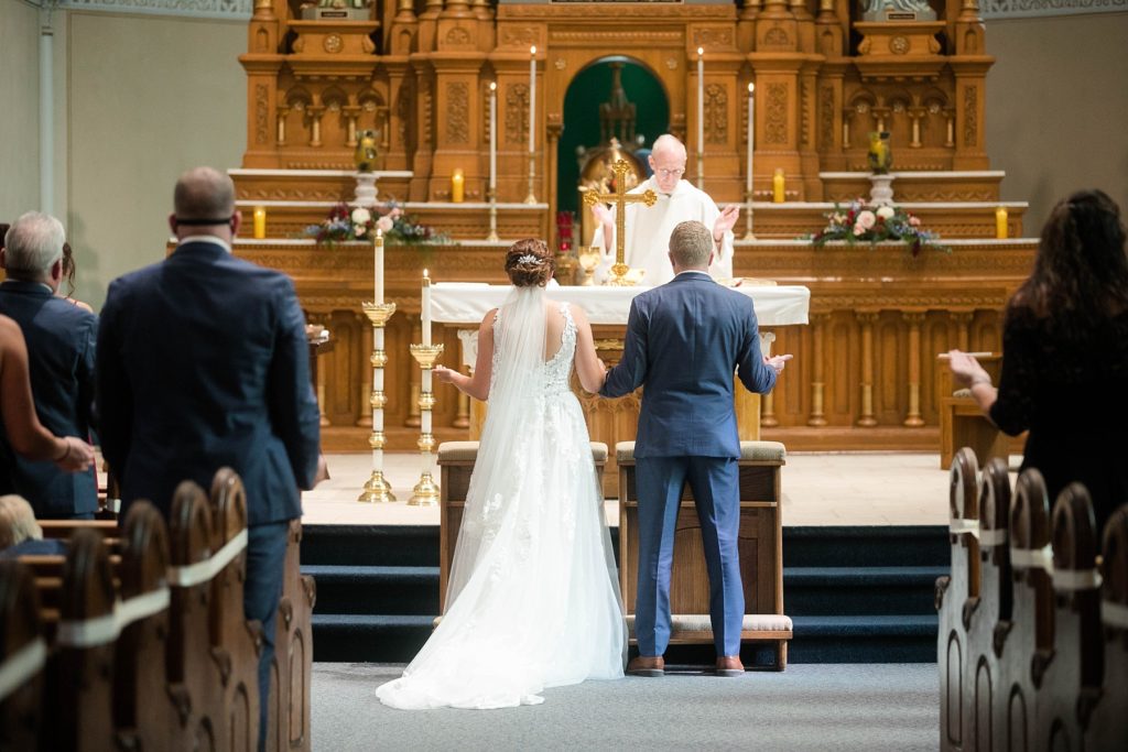 priest giving a blessing at stunning wedding in Marathon, WI at St. Mary's Catholic Church