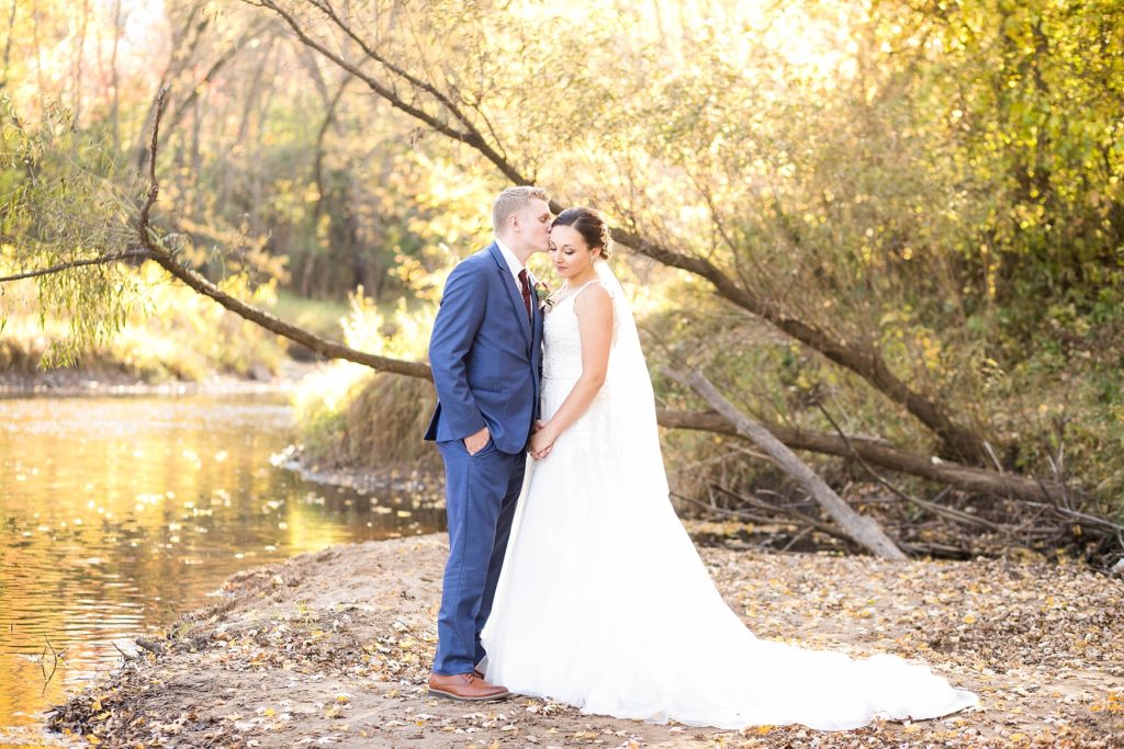 bride and groom standing on the shore of a creek at stunning wedding in Marathon, WI 