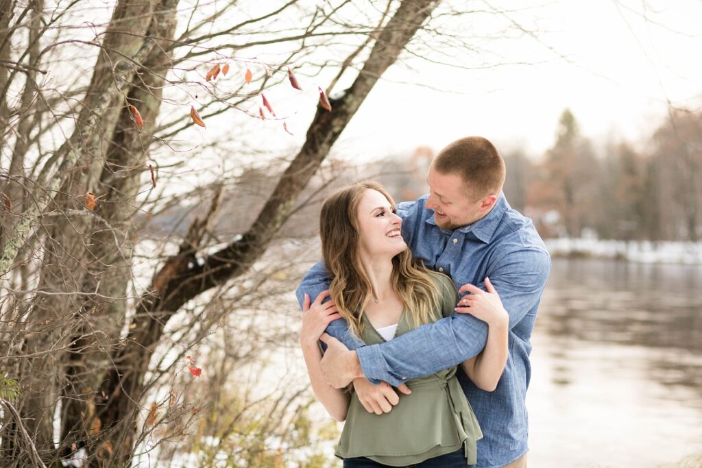 couple standing near open water by the Chippewa River for their winter engagement session in Ladysmith